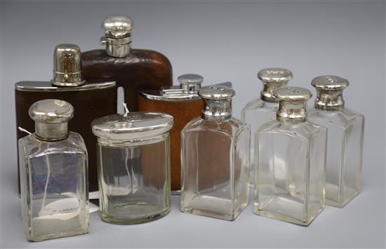 A silver-mounted hip flask, two other hip flasks and a quantity of toilet bottles